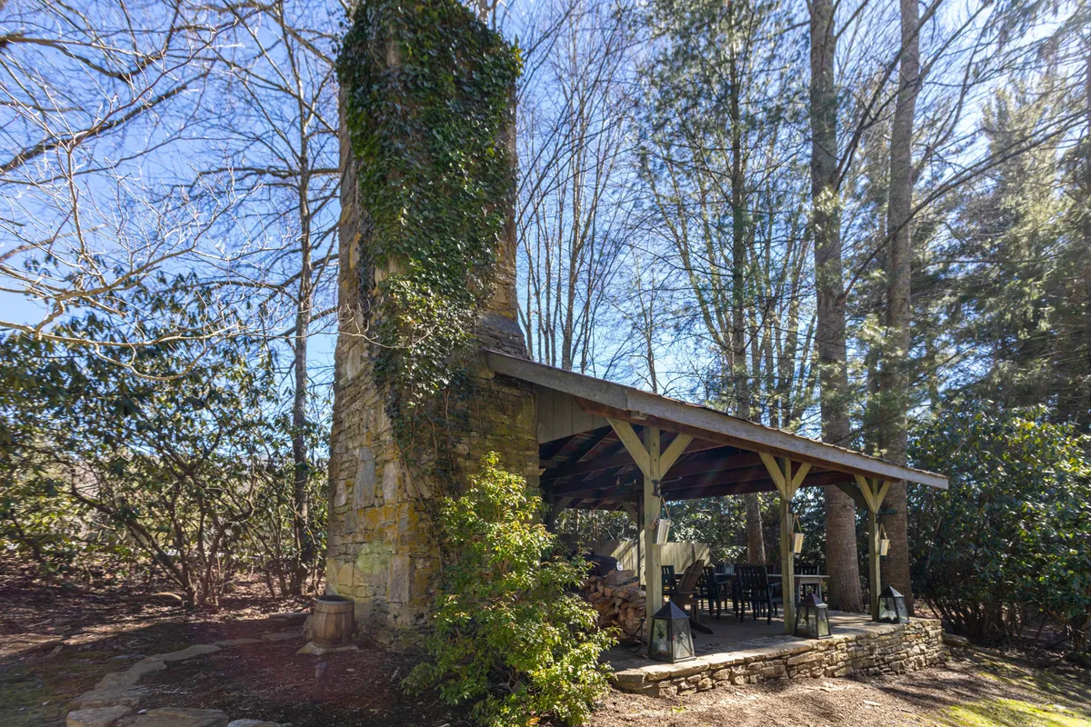 This image presents an inviting outdoor seating area with a stone chimney and wooden structure, ideal for gatherings around a fireplace or enjoying a morning coffee in nature. The cozy ambiance and outdoor connection match the theme of exploring local venues and returning to a welcoming retreat.
